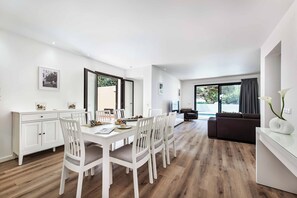 A modern living room with a dining area, a sofa, and a TV. - Villa Maria Luisa - Four Bedroom Villa, Sleeps 8 (Olhos de Água)