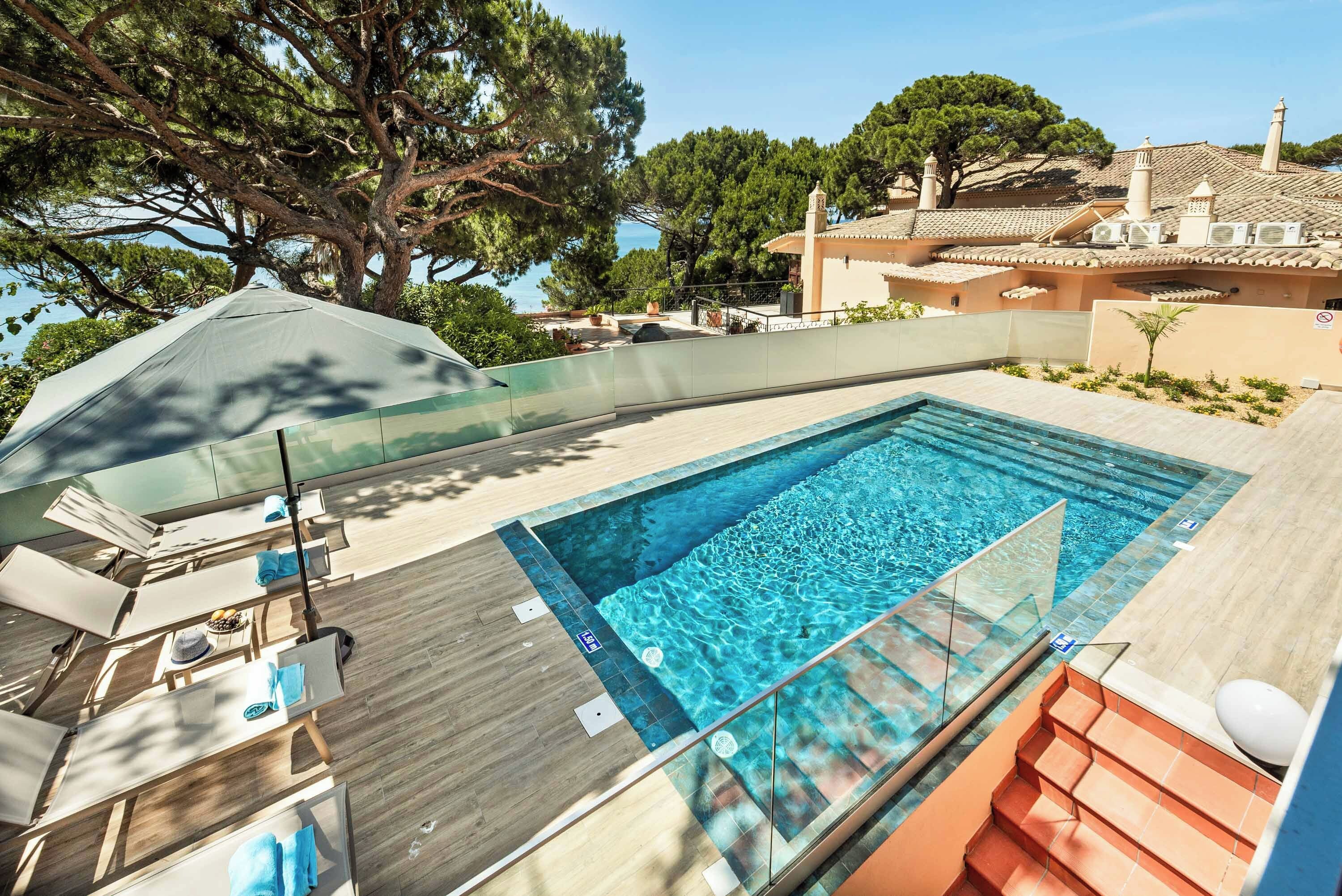 Ein Pool auf dem Dach mit klarem, blauem Wasser, umgeben von einer Holzterrasse und Liegestühlen.