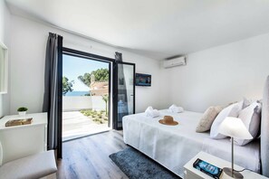 A modern hotel room with a bed, a desk, a TV, and a view of the outdoors. - Villa Maria Luisa - Four Bedroom Villa, Sleeps 8 (Olhos de Água)