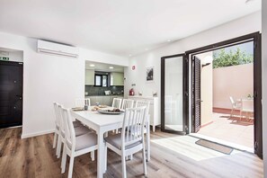 A modern kitchen with white cabinets and a dining area with a white table and chairs. - Villa Maria Luisa - Four Bedroom Villa, Sleeps 8 (Olhos de Água)