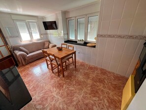 Um espaço de estar compacto com área de refeições, sofá e TV na parede.