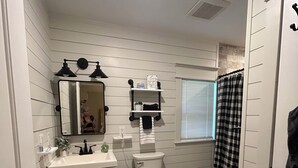 Une salle de bain équipée de toilettes, d’un lavabo, d’un miroir et d’un rideau de douche.