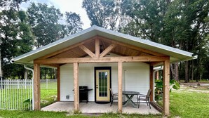 Un espace extérieur abrité avec un barbecue, une table et des chaises.