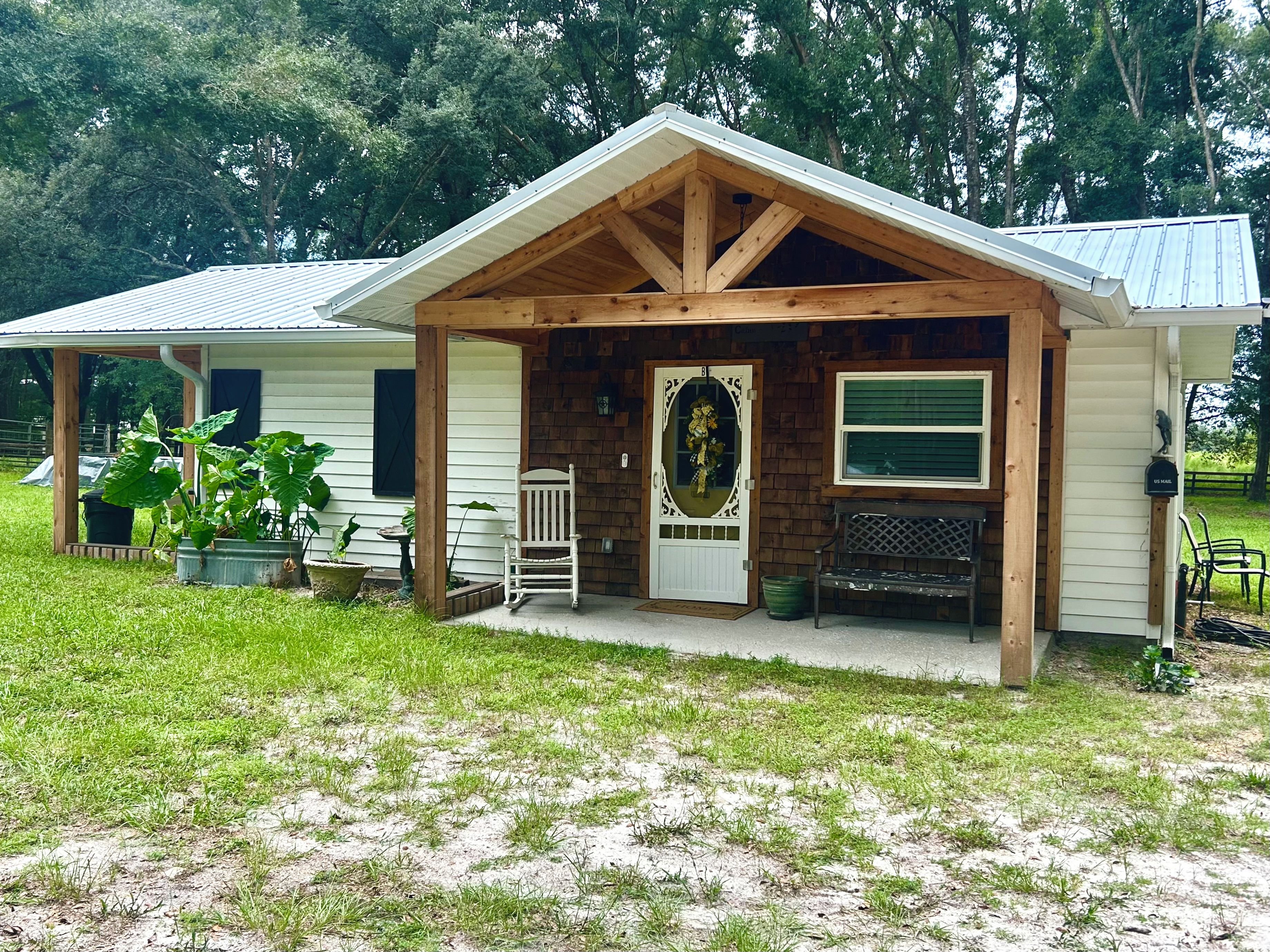 A wooden cabin with a porch, a mailbox, and a bench.