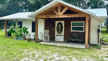A wooden cabin with a porch, a mailbox, and a bench.