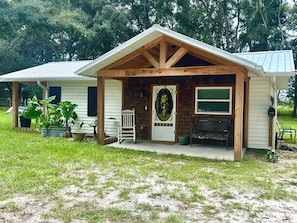A wooden cabin with a porch, a mailbox, and a bench.