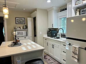A modern kitchen with white cabinets, a microwave, an oven, and a refrigerator.