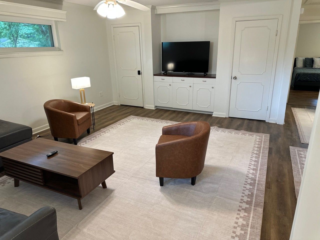 A living room with a TV, two brown armchairs, a coffee table, and a lamp.