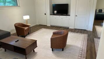 A living room with a TV, two brown armchairs, a coffee table, and a lamp.