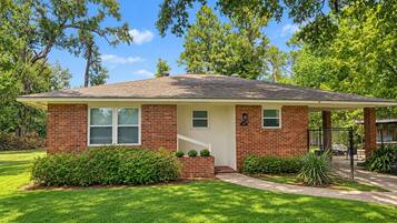 A single-story brick house with a front porch, a small front yard, and a mailbox.