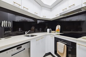 A modern kitchen with a dishwasher, sink, and a set of knives. - Ocea Coastal Luxe at Chevron (Surfers Paradise)