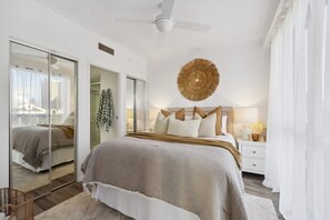 Ein Schlafzimmer mit einem Bett, Nachttisch, Lampe und einem großen Spiegel.
