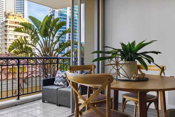 A balcony with a round table, two chairs, and potted plants. - Ocea Coastal Luxe at Chevron (Surfers Paradise)