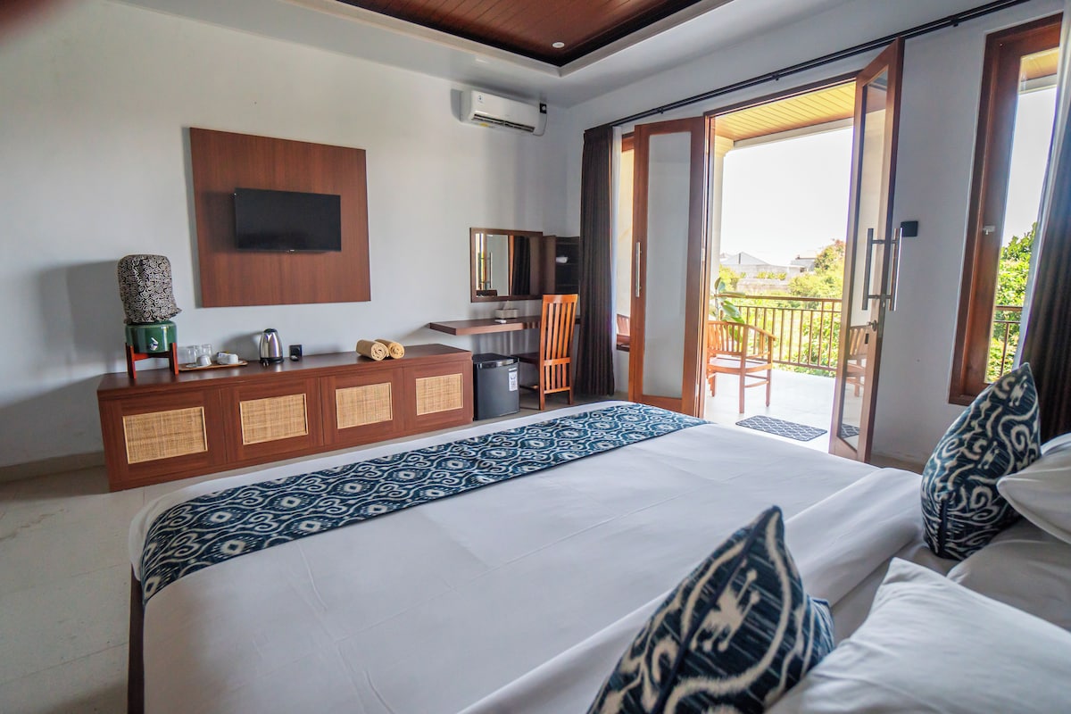 Een hotelkamer met een bed, een bureau, een stoel, een televisie en een schuifdeur naar een balkon.