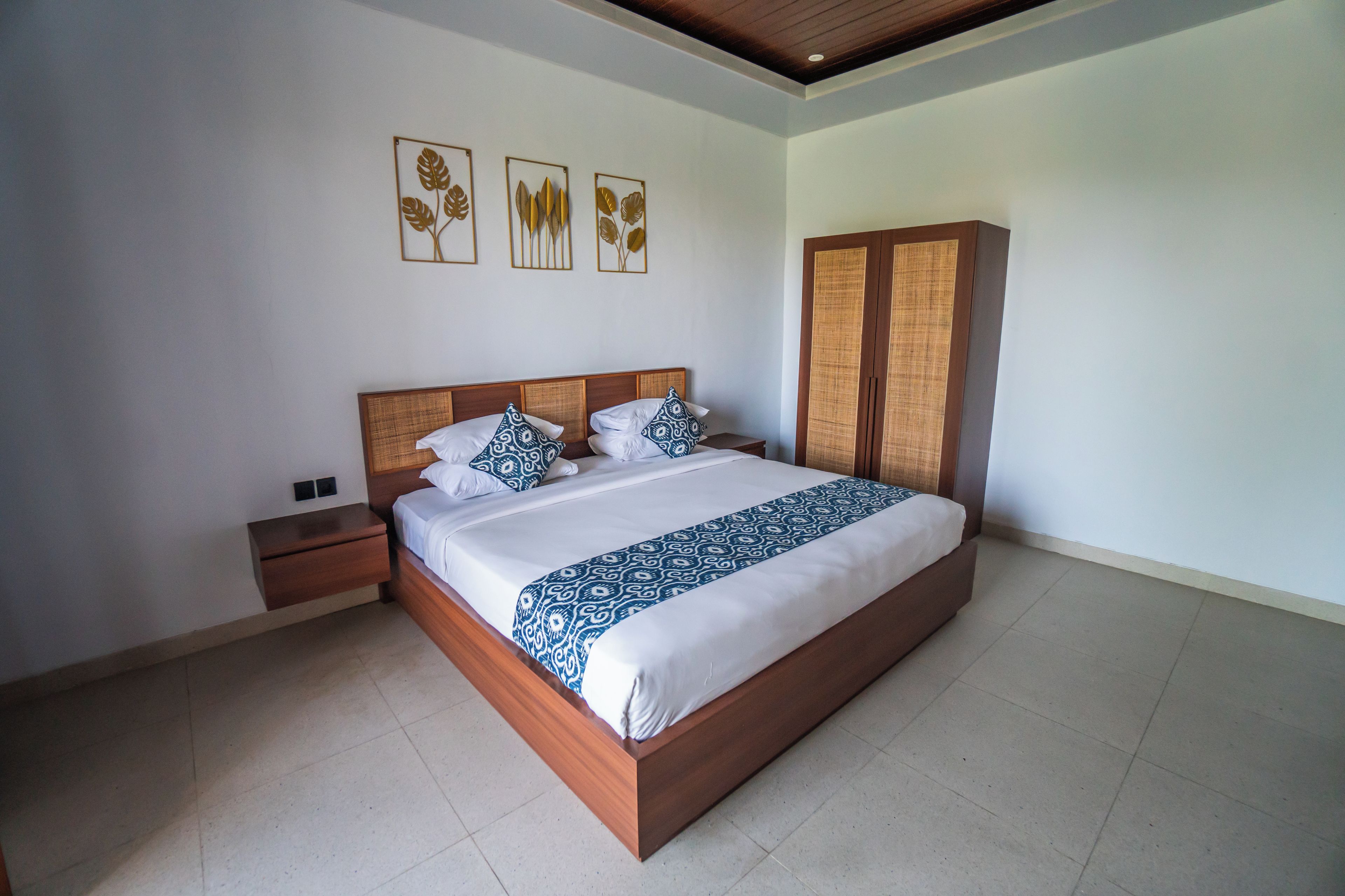 Un dormitorio con cama de madera, ropa de cama blanca, una mesita de noche, un armario y decoración en la pared.