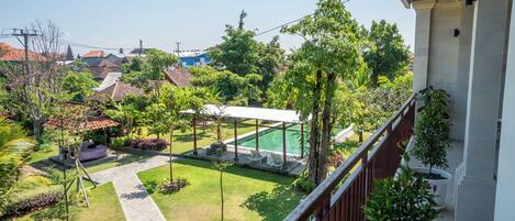 A residential area with a swimming pool, garden, and a view of neighboring houses.