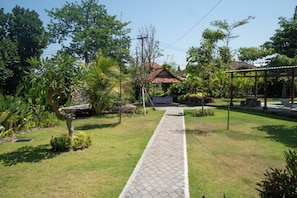 A pathway leading to a traditional house with a tiled roof, surrounded by lush greenery and a clear sky. - Campuan Sari Villa (Denpasar)