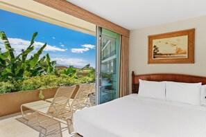 Ein Hotelzimmer mit Bett, einem Gemälde und Blick auf üppige tropische Vegetation.