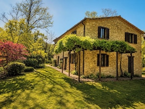 A stone building with a garden pathway leading to the entrance. - Stone farmhouse in the Umbrian hill countryside (Montone)