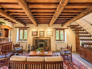 A cozy living room with a fireplace, wooden furniture, and a staircase. - Stone farmhouse in the Umbrian hill countryside (Montone)