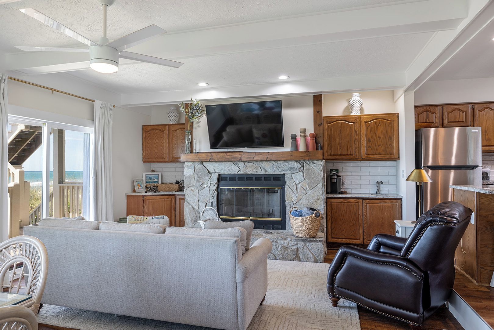 A modern living room with a stone fireplace, a flat-screen TV, and a leather recliner.