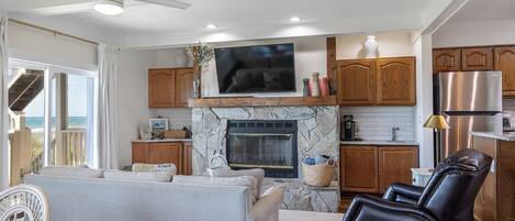 A modern living room with a stone fireplace, a flat-screen TV, and a leather recliner.