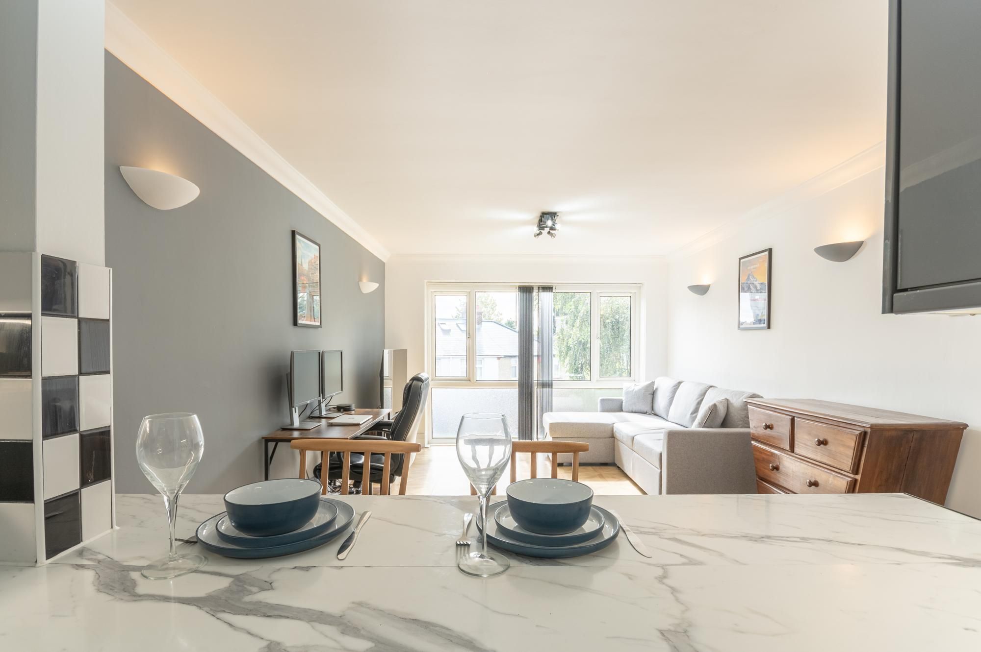 Un salon moderne comprenant un coin repas, un canapé, un téléviseur et une grande fenêtre.