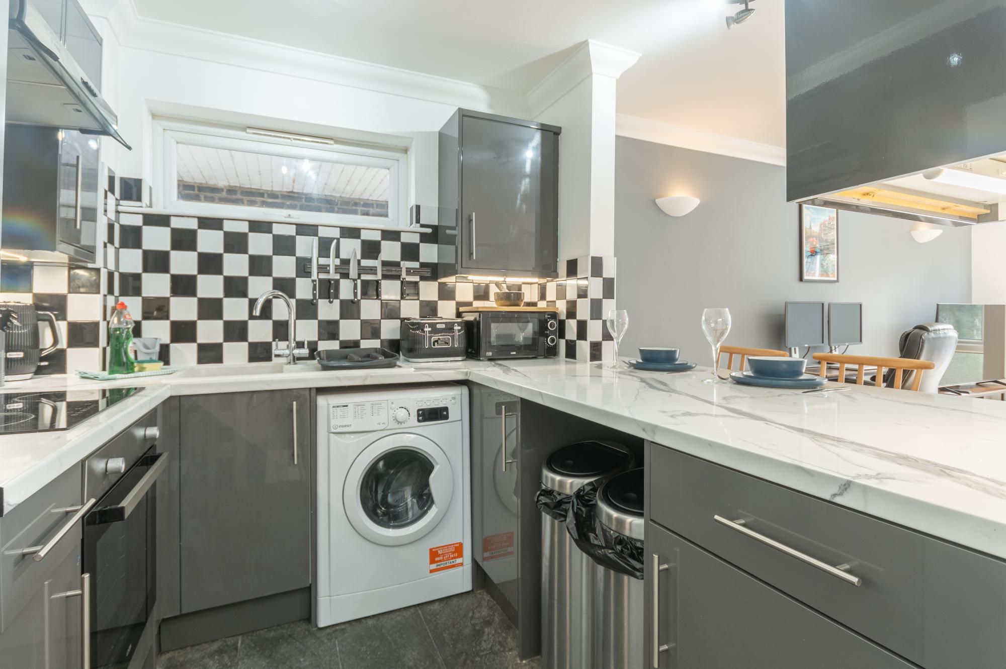 A compact kitchen with a washing machine, a microwave, and a toaster.
