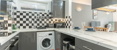 A compact kitchen with a washing machine, a microwave, and a toaster.