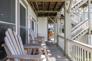 A wooden deck with Adirondack chairs, a staircase, and a view of a residential building. - Pier Pointe 4B1 | Oceanfront 2 BR Condo (Emerald Isle)