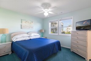 A bedroom with a bed, nightstands, a dresser, a ceiling fan, and a window with a view. - Pier Pointe 4B1 | Oceanfront 2 BR Condo (Emerald Isle)