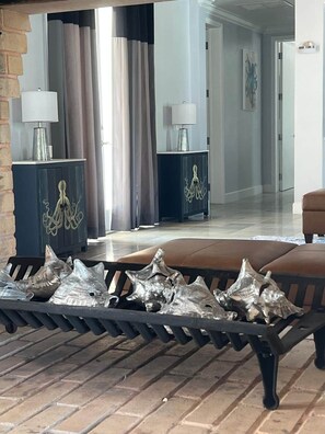 A living room with a sofa, a coffee table, and decorative shells. There are two lamps on side tables, and a hallway is visible in the background. - SlipAway TreasureCay (Treasure Cay)