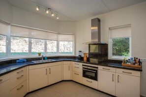 A modern kitchen with a large island, built-in oven, and ample counter space. - NEW: Beachfront Blue Bay Beach Ocean 13 (Sint Michiel)