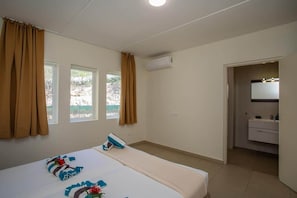 A hotel room with a bed, a bathroom, and a view of the outdoors. - NEW: Beachfront Blue Bay Beach Ocean 13 (Sint Michiel)