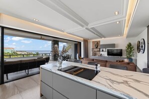 A modern kitchen with a large island, a dining area with a view, and a living space with a flat-screen TV. - NEW: Beachfront Blue Bay Resort The Shore 6 (Sint Michiel)