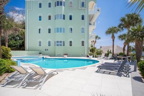 A swimming pool with lounge chairs, a building with balconies, and palm trees. - NEW: Beachfront Ocean Suite 5 Blue Bay Beach (Sint Michiel)
