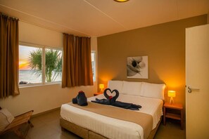 Een hotelkamer met een bed, een stoel, een nachtkastje en een raam met gordijnen.