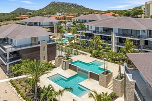 Ein Resort mit mehreren Gebäuden, einem zentralen Poolbereich und umliegender Bepflanzung.