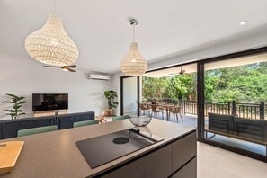 A modern kitchen with a central island, pendant lights, and a view to an outdoor balcony. - NEW: Blue Bay Beach Resort The Breeze Oasis (Sint Michiel)