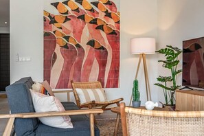 A living room with a sofa, a chair, a lamp, and a large abstract painting on the wall. - NEW: Blue Bay Beach Resort The Breeze Oasis (Sint Michiel)