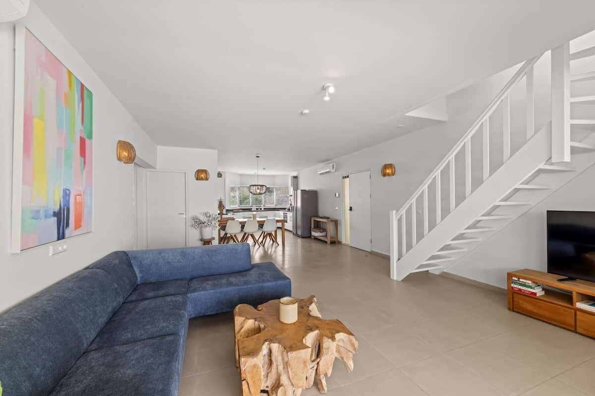 Een moderne woonkamer met een blauwe bank, een houten salontafel en een tv op een houten dressoir.