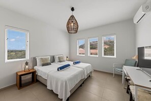 A bedroom with two beds, a desk, and a television. - NEW: Blue Bay Beachfront Penthouse 3BDR (Sint Michiel)