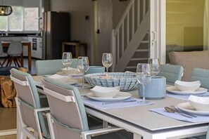 A dining area with a table set for four, including plates, bowls, and wine glasses. - NEW: Blue Bay Beachfront Penthouse 3BDR (Sint Michiel)