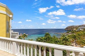 A balcony with a view of the sea and a rocky coastline. - NEW: Blue Bay Beachfront Penthouse 3BDR (Sint Michiel)