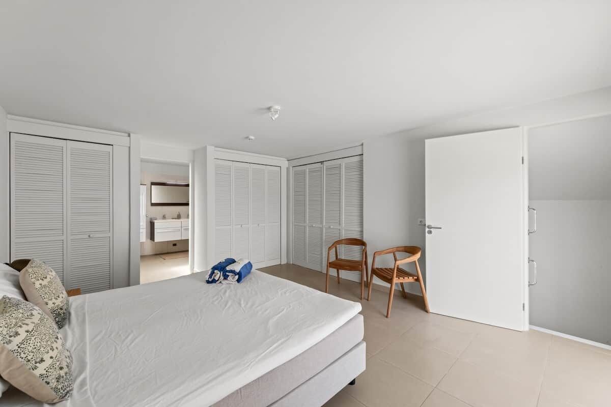 Un dormitorio con una cama, una silla y un armario.
