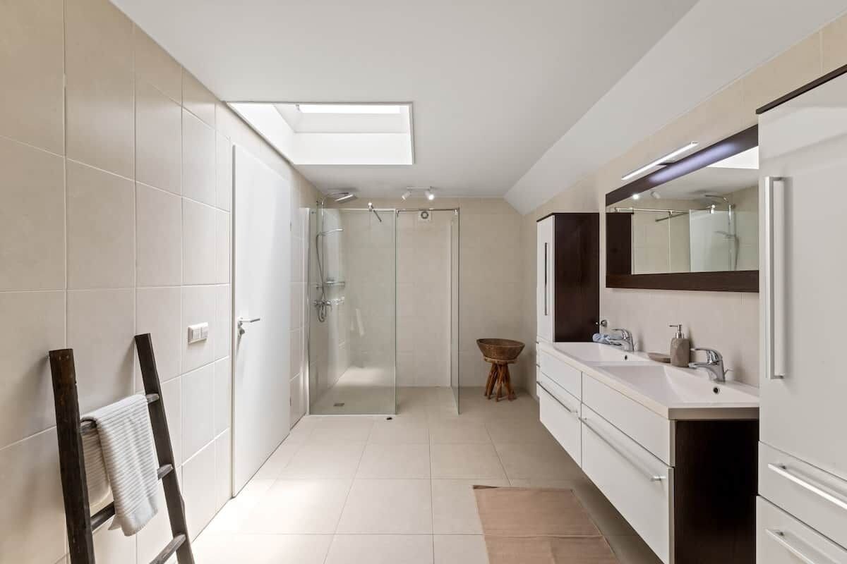 Un baño moderno con cabina de ducha de vidrio, un espejo grande y un perchero para toallas.