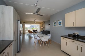 A modern kitchen with a dining area, a ceiling fan, and a view to the outside. - NEW: Blue Bay Beachfront Ocean Suite 23 (Sint Michiel)
