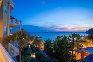 A resort with a pool, palm trees, and a view of the ocean at dusk. - NEW: Blue Bay Beachfront Ocean Suite 23 (Sint Michiel)