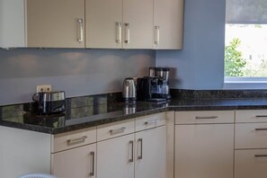 A kitchen with a coffee maker, a kettle, and a blender on the counter. - NEW: Blue Bay Beachfront Ocean Suite 23 (Sint Michiel)