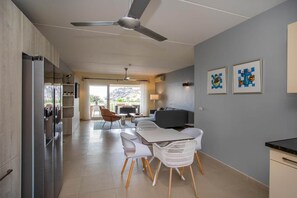 A modern kitchen with a dining area, a ceiling fan, and artwork on the wall. - NEW: Blue Bay Beachfront Ocean Suite 23 (Sint Michiel)